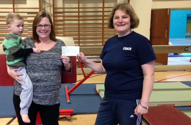 Pre-School class parent Katy Glynn and son hand over a cheque for £726 to coach Becca Hamm from MoneySuperMarket